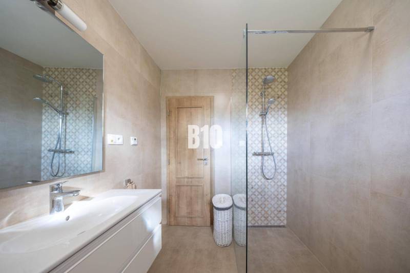 Fürdőszoba kerámia burkolattal, zuhanyzóval és tükörrel egy családi házban.