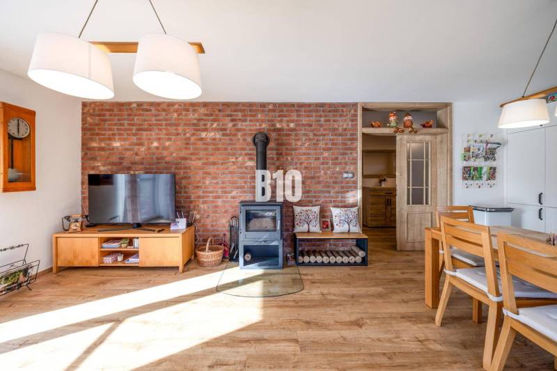 Családi ház belső tere téglafallal, kályhával és fa dekorációjú padlóval.