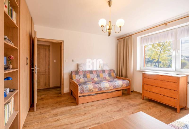 Szoba egy családi házban, fa mintázatú padlóval, kanapéval és komóddal.