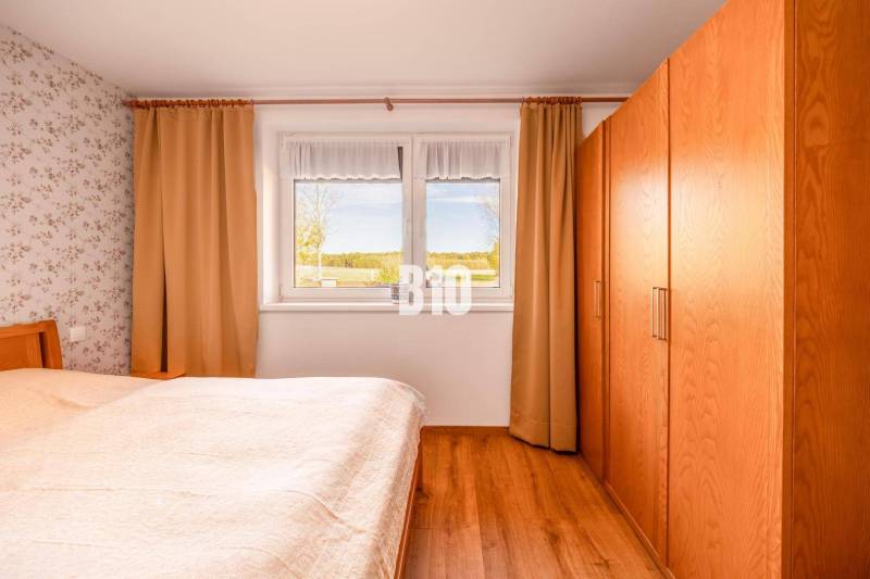 Hálószoba családi házban, fa dekoros padlóval és kilátással az ablakból.