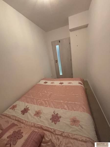 Hálószoba egy kétszobás lakásban, virágmintás ággyal és világos falakkal.