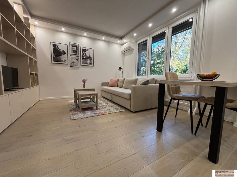 Nappali egy kétszobás lakásban, nagy kanapé, asztal, fa dekorációjú padló.