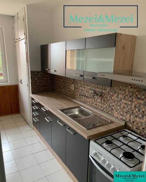 Konyha egy kétszobás lakásban sötét bútorokkal és csempézett burkolattal.