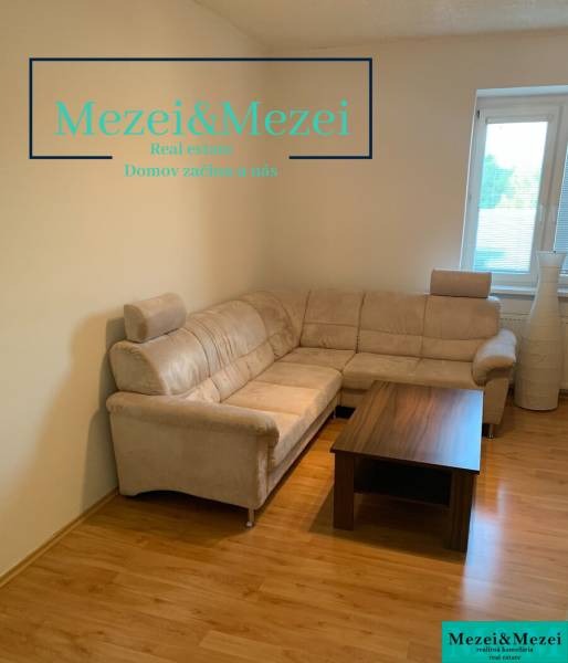 Nappali egy kétszobás lakásban sarokkanapéval és asztallal, fa dekorációjú padlón.