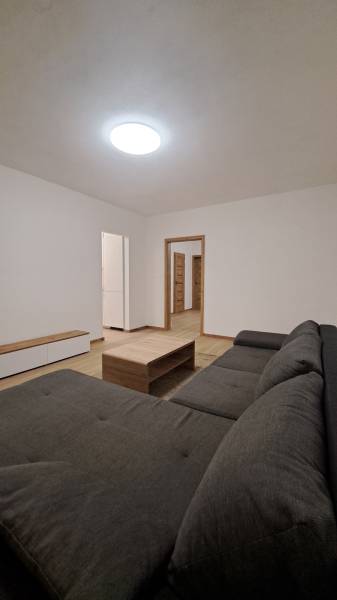 Nappali kényelmes kanapéval, faasztallal és fa dekorációjú padlóval.