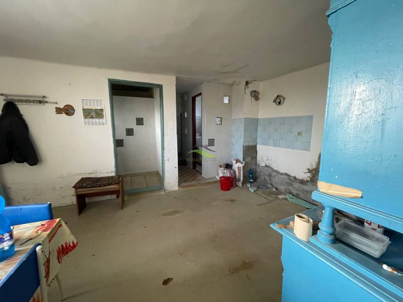 Egy családi ház belső tere egyszerű bútorokkal és kék szekrénnyel.