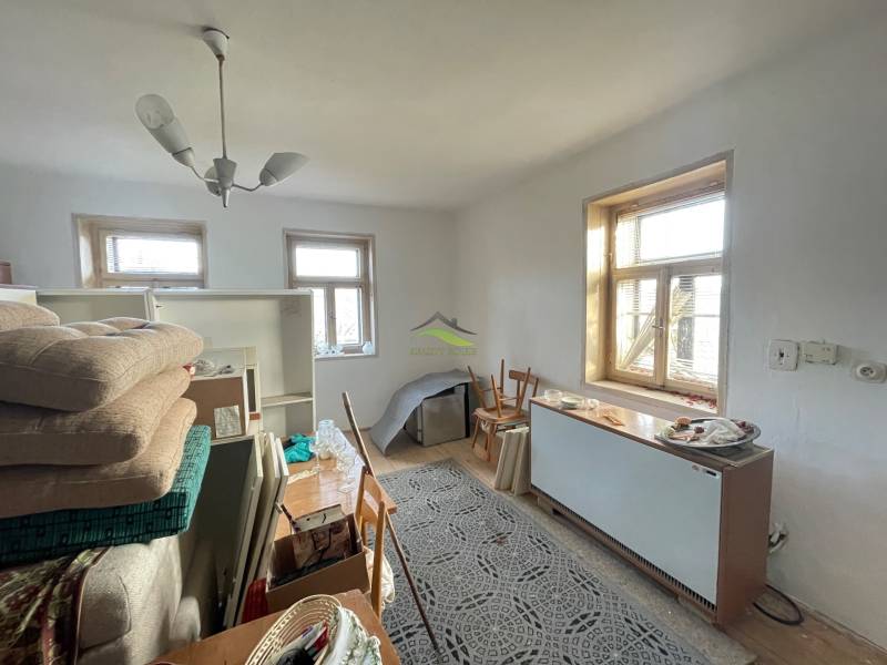 Családi ház belső tere kanapéval, asztallal, szőnyeggel és nagy ablakokkal.