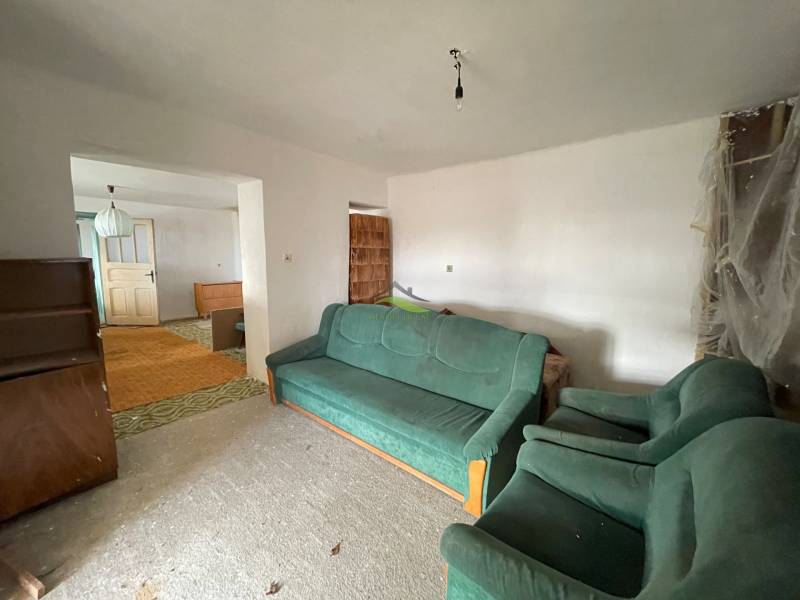 Nappali egy családi házban szőnyegekkel és zöld kárpitozott bútorokkal.