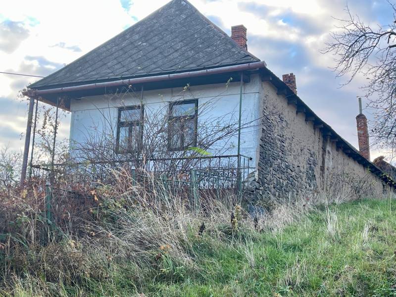 Családi ház a Fő utcán Felsőremetén, elhanyagolt kerttel és régi falakkal körülvéve.