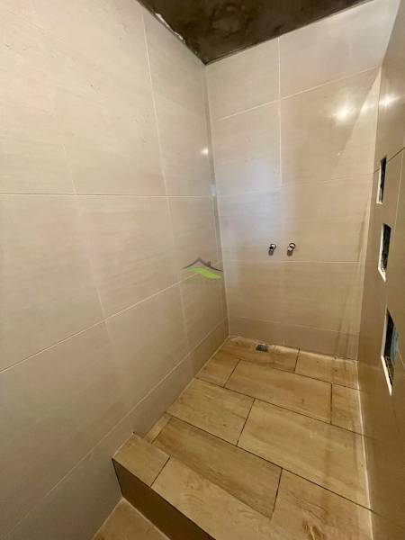 Fürdőszoba családi házban, csempézett falakkal és fa dekoros padlóval.