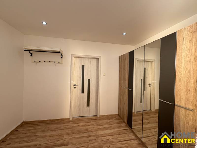 Szoba egy háromszobás lakásban, fa dekoros padlóval és tükrös szekrénnyel.