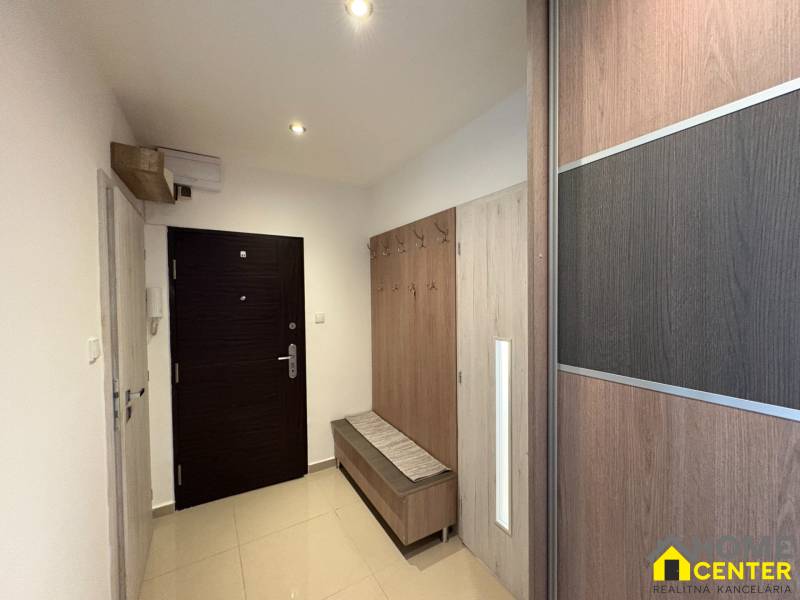 A háromszobás lakás előszobája szekrénnyel és fogassal, világos környezetben.