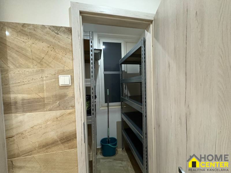 Kis raktár egy háromszobás lakásban polcokkal és vödörrel.