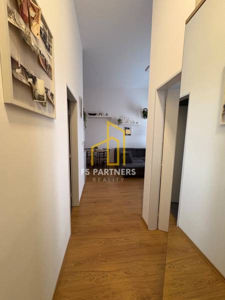 Folyosó egy kétszobás lakásban, fa dekoros padlóval és falakon lévő dekorációkkal.