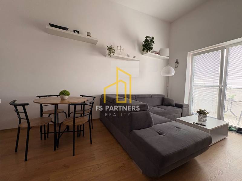 Nappali sötétszürke kanapéval és fa mintázatú padlóval egy kétszobás lakásban.