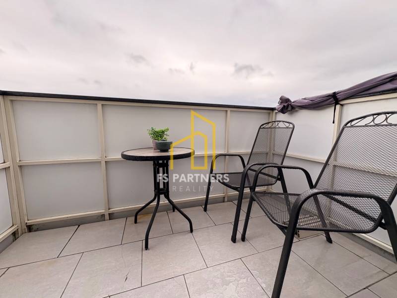 A komáromi kétszobás lakás erkélye két székkel és egy asztallal a csempén.