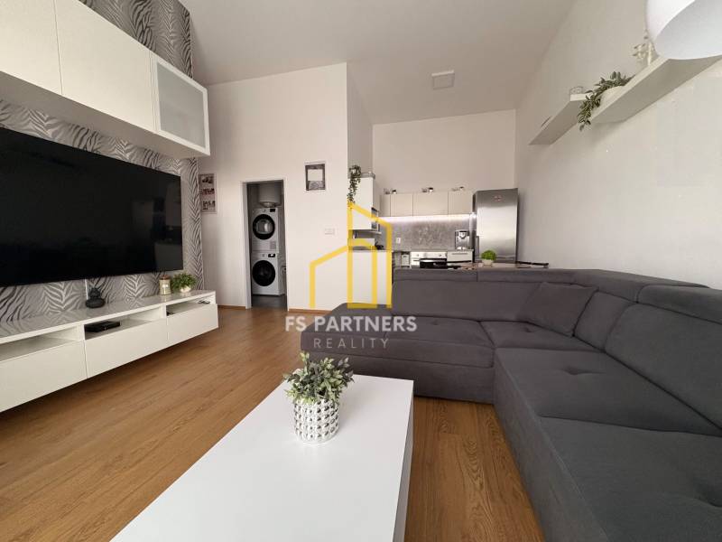 Nappali nagy kanapéval, fa dekoros padlóval és televízióval egy kétszobás lakásban.