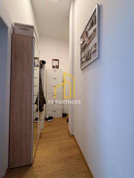 Keskeny folyosó egy kétszobás lakásban, fa dekorációjú padlóval és gardróbbal.