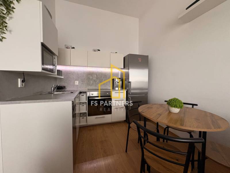 Konyha egy kétszobás lakásban fa dekoros padlóval és étkezőasztallal.