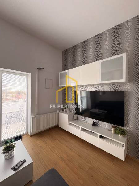 Nappali TV-fallal, mintás tapétával és fa dekoros padlóval egy kétszobás lakásban.