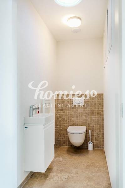 WC mosdóval, világos színű falakkal és csempével családi házban.