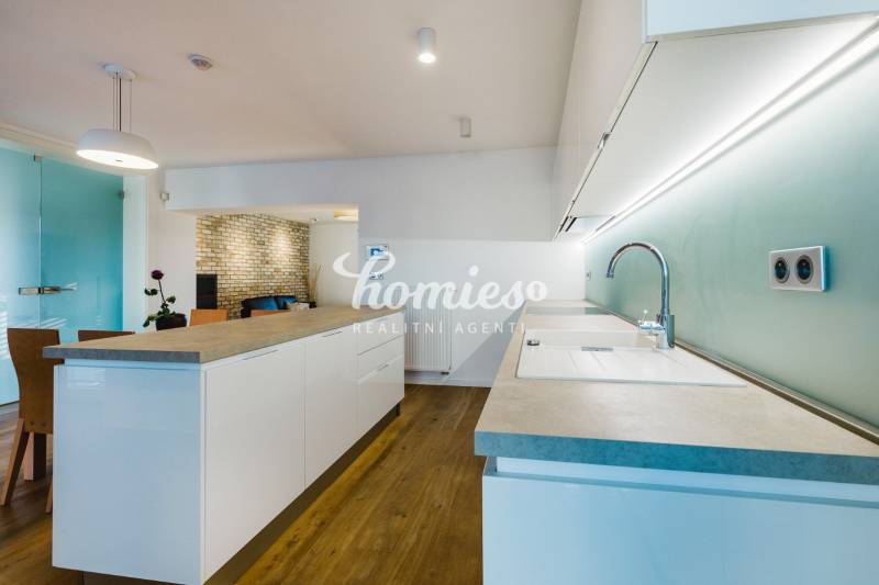 Konyha szigettel, téglafallal és fa dekoros padlóval a családi házban.