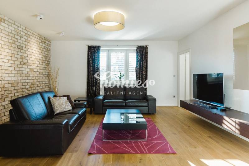 Nappali bőrkanapéval, téglafallal és fa mintázatú padlóval egy családi házban.