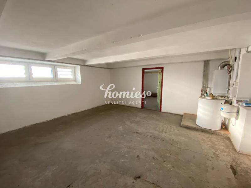 Üres szoba egy családi házban ablakokkal és kazánnal.