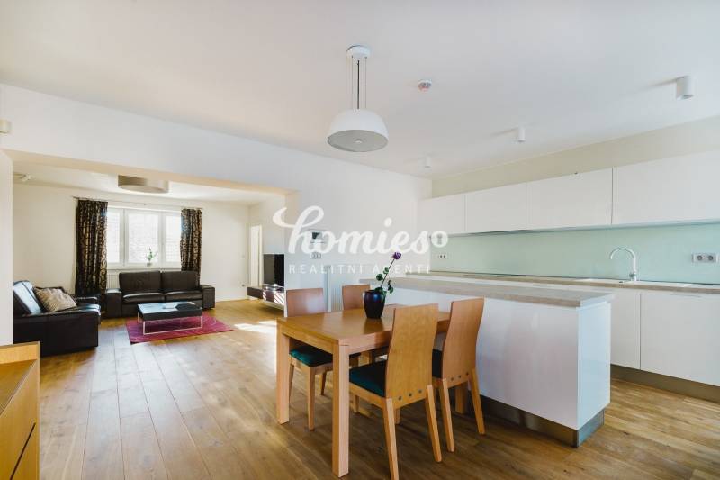 Konyha és nappali családi házban, fa hatású padlóval és világos bútorokkal.