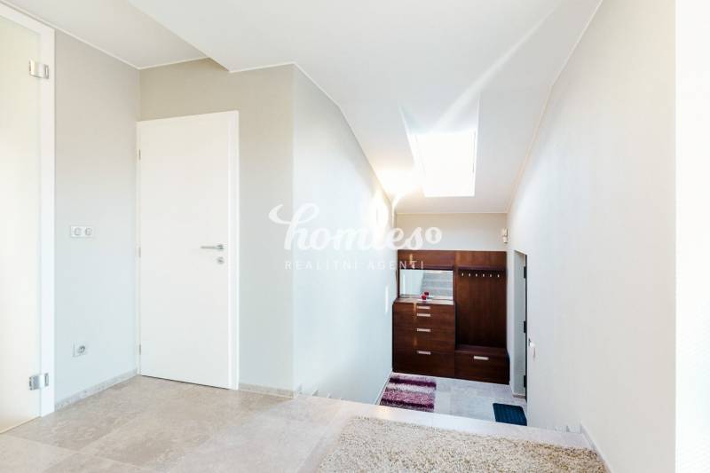 Családi ház belső tere járólappal és fehér falakkal, lépcsőház és tetőablak.