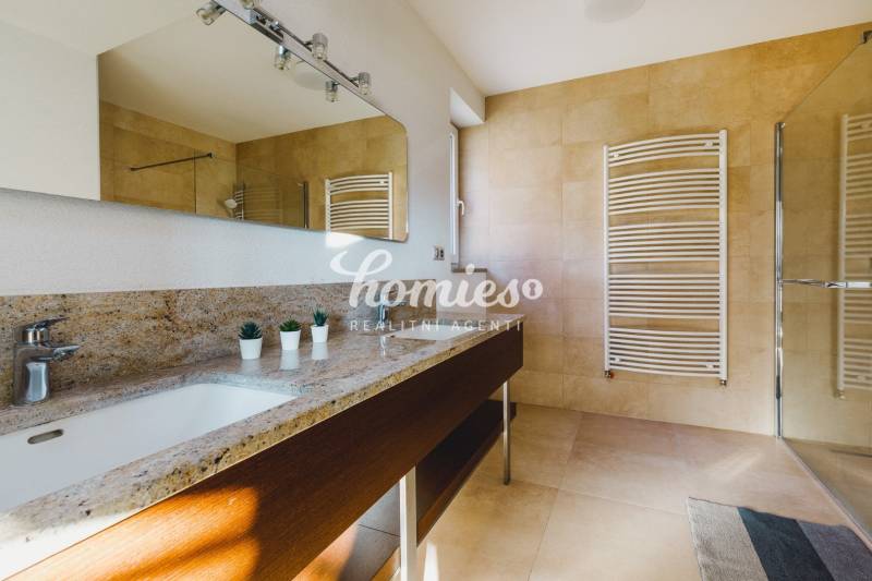 Fürdőszoba családi házban kőmosdóval, tükörrel és nagy ablakkal.