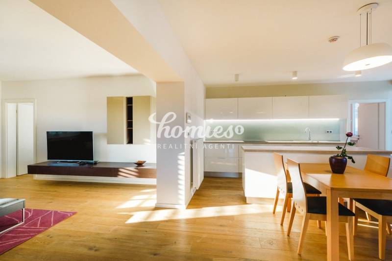 Családi ház nyitott konyhával, fa dekorációjú padlóval és étkezőasztallal.