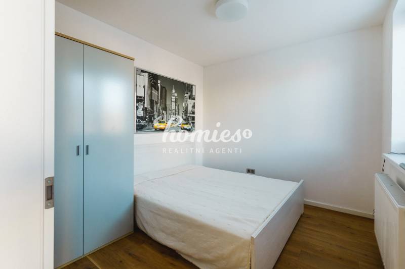 Hálószoba családi házban, egyszerű ággyal, szekrénnyel és fa dekorációjú padlóval.