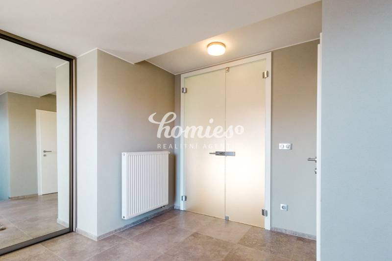 Minimalista dizájnú előszoba egy családi házban, tükörrel és világos falakkal.