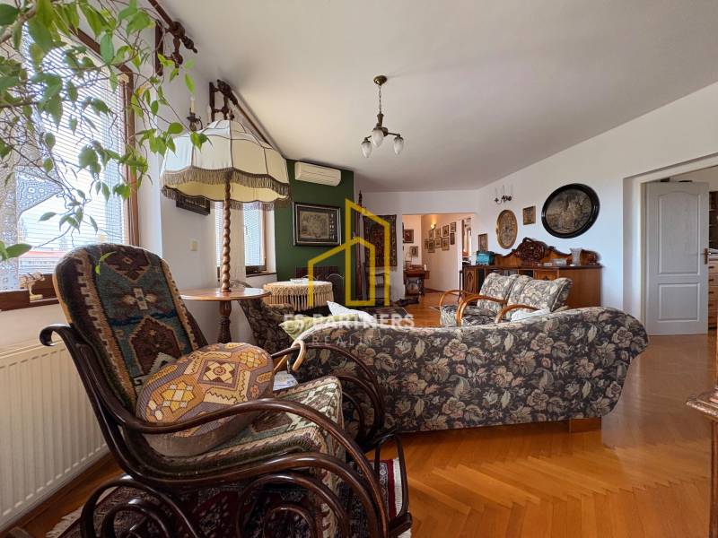 Nappali egy öt vagy több szobás lakásban, fa dekoros padlóval és vintage bútorokkal.