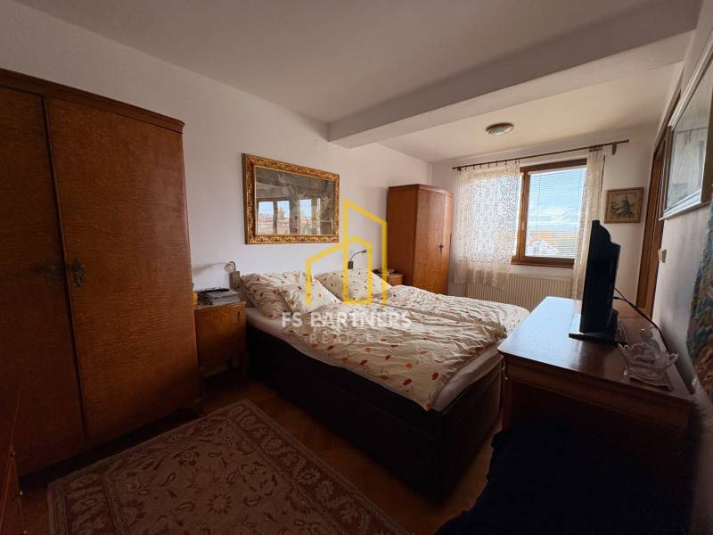 Hálószoba egy 5 vagy több szobás lakásban, szőnyeggel és fa szekrényekkel.