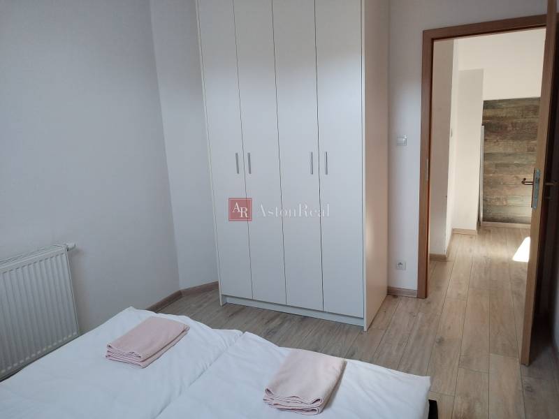 Hálószoba egy faházban fehér ruhásszekrénnyel és fa mintázatú padlóval.