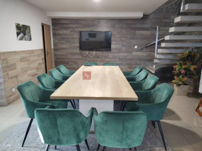 Ebédlő faházban fa dekorációval, lépcsővel és zöld székekkel az asztal körül.