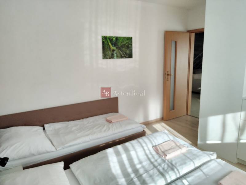 Két ágy a szobában, egy képpel a falon és ajtóval a házikóban.