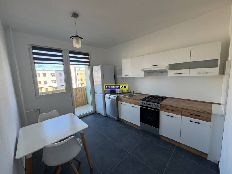 Konyha egy 3 szobás lakásban fehér bútorokkal és étkezőasztallal.