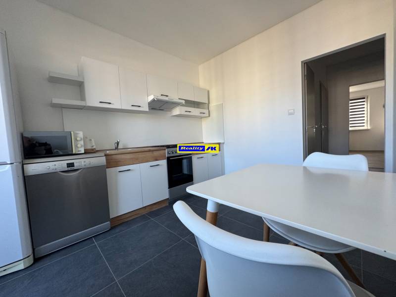 Egy háromszobás lakás konyhája fehér bútorokkal és készülékekkel, kerámia csempézett padlóval.