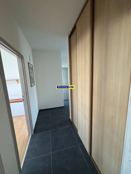 Folyosó egy 3 szobás lakásban sötét csempével és beépített szekrénnyel.