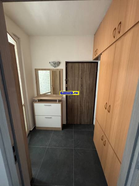 Folyosó sötét csempével és beépített szekrénnyel egy háromszobás lakásban.