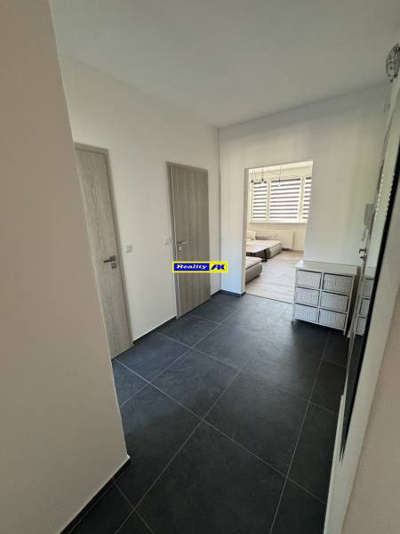 Előszoba egy háromszobás lakásban sötét burkolattal és világos ajtókkal.