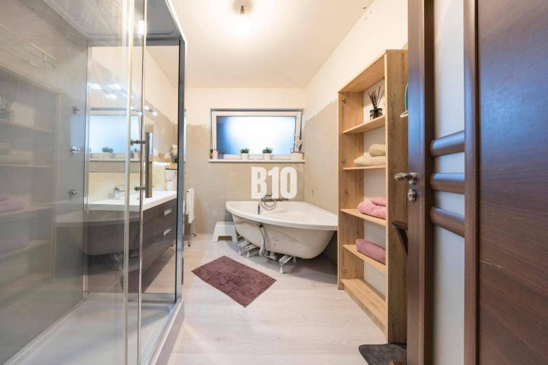 Fürdőszoba családi házban káddal, zuhanyzóval és fa dekorációjú bútorokkal.