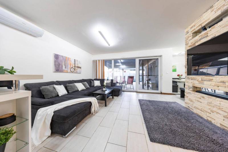 Nappali egy családi házban kanapéval, kandallóval és tolóajtókkal a teraszra.