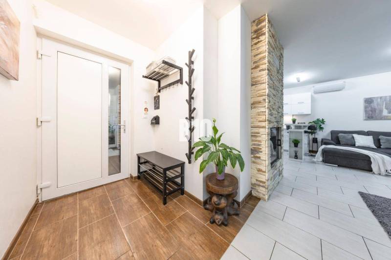 Családi ház belső tere fa dekoros padlóval, kő kandallóval és kényelmes nappalival.