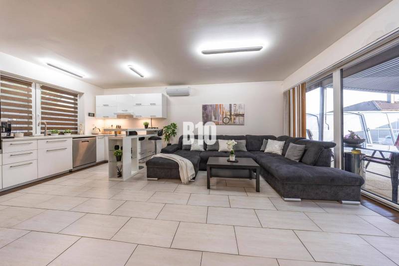 Világos nappali családi házban konyhával és nagy kanapéval.