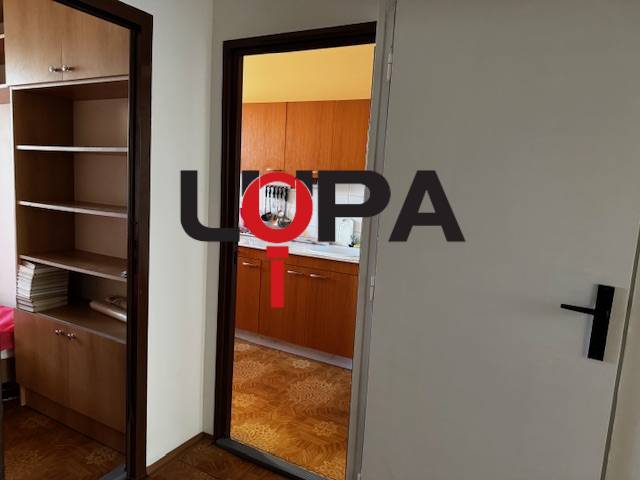 Folyosó a konyhába való bejárattal, fa dekorációjú padló egy háromszobás lakásban.