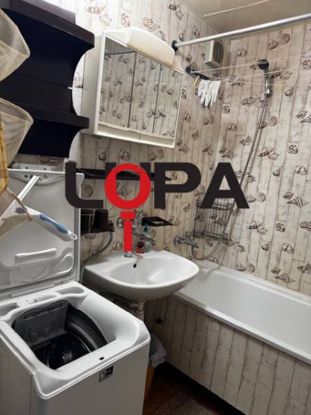 Fürdőszoba egy háromszobás lakásban káddal, mosdóval és mosógéppel, tapéta dekorációval.